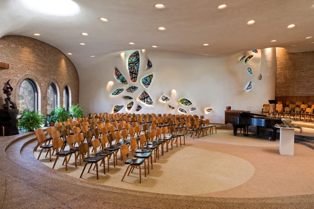 A panoramic photograph of the interior of our sanctuary, highlighting our fused glass windows and organic walls and ceiling.